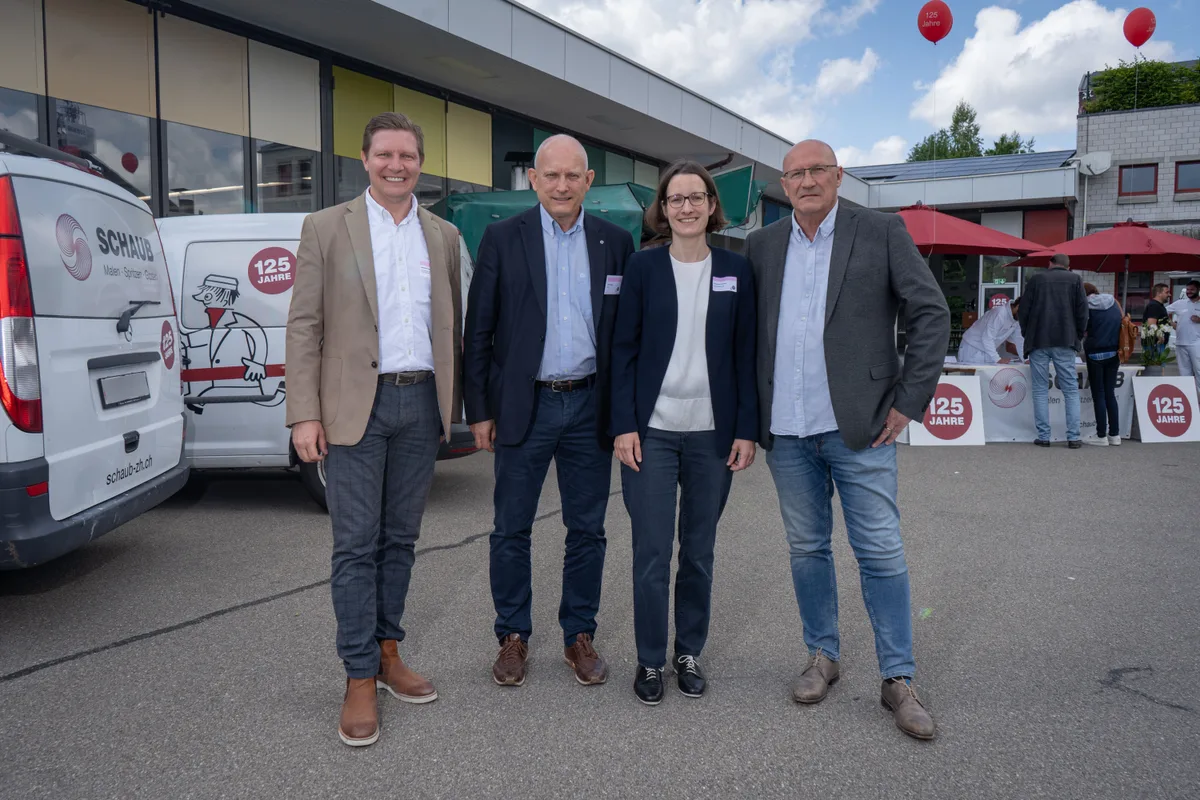 Gruppenbild mit drei Männern und einer Frau. Sie posieren vor weissen Lieferwagen der Schaub Maler AG.